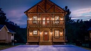Une cabane en bois à deux étages, dotée d’un porche à l’avant, de nombreuses fenêtres et d’une entrée bien éclairée.