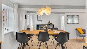 Un comedor con una mesa de madera, sillas negras y una araña.