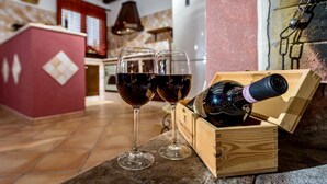 A wooden wine chest with a bottle of wine and two glasses on a kitchen counter.