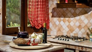 A kitchen counter with a bottle of olive oil, a loaf of bread, a head of cauliflower, and some tomatoes.