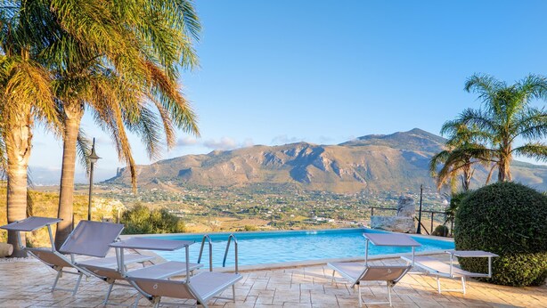 A pool area with lounge chairs and a view of mountains. - Villa Luisa - Scopello (Scopello)