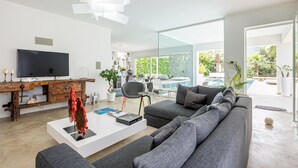 A modern living room with a large flat-screen TV, grey sofas, a white coffee table, and a wooden console table. - Villa Marianna - Terrasini (Terrasini)