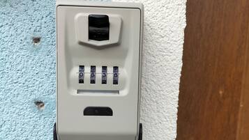 A wall-mounted intercom system with a numeric keypad and a speaker grille.