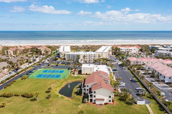 A coastal hotel with a tennis court, pool, and ocean view.