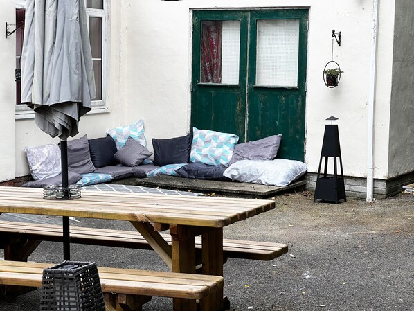 Een houten bank en een picknicktafel voor een gebouw met een groene deur en witte muren.