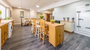 A modern kitchen with wooden cabinets, a central island, and a dining area with wooden chairs.