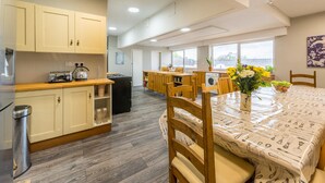 A modern kitchen with wooden cabinets, a built-in stove, and a dining area with a table set for two.