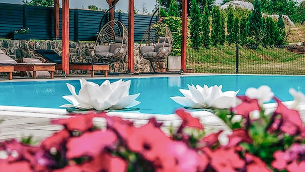 Une piscine agrémentée de deux éléments décoratifs en forme de lotus blancs, entourée de fleurs roses.