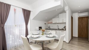 Un espace repas moderne avec une table ronde, des chaises blanches et une vue sur la cuisine.