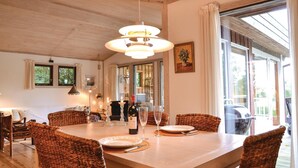 Zona pranzo con tavolo in legno, sedie in vimini e lampadario.