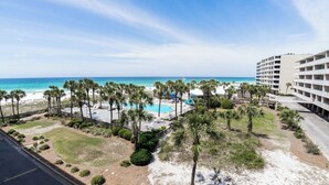 Een resort met een zwembad, palmbomen en uitzicht op het strand.