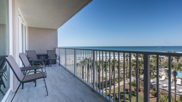 Ein Balkon mit Blick auf den Strand, einen Pool und Palmen.
