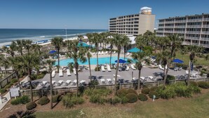 Ein Hotel mit Poolbereich, Palmen und Blick auf den Ozean.