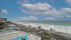 A beach resort with a swimming pool, lounge chairs, and a view of the ocean. - D406 Corner Unit, Great View of Pool and Direct Gulf View (Panama City Beach)