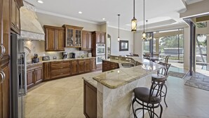 A spacious kitchen with wooden cabinets, a large island, and a dining area with bar stools.