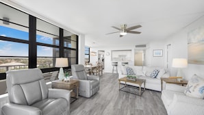 A spacious living area with a view, modern furniture, and a ceiling fan. - Corner Beachfront Condo | Gym, Pool & Grills (Marco Island)