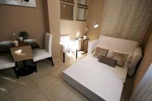 A compact hotel room with a bed, a desk, a chair, and a small table.