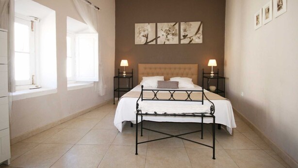 A bedroom with a bed, two bedside tables, a window with curtains, and wall-mounted artwork. - Apartamento Constitución Málaga (Málaga)