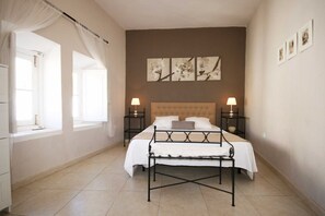 Ein Schlafzimmer mit einem Bett, zwei Nachttischen, einem Fenster mit Vorhängen und Wandbildern.