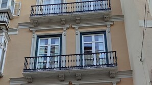 A multi-story building with a Carrefour Express store on the ground floor, featuring a large wooden door and a sign indicating open Sundays and holidays. - Apartamento Constitución Málaga (Málaga)