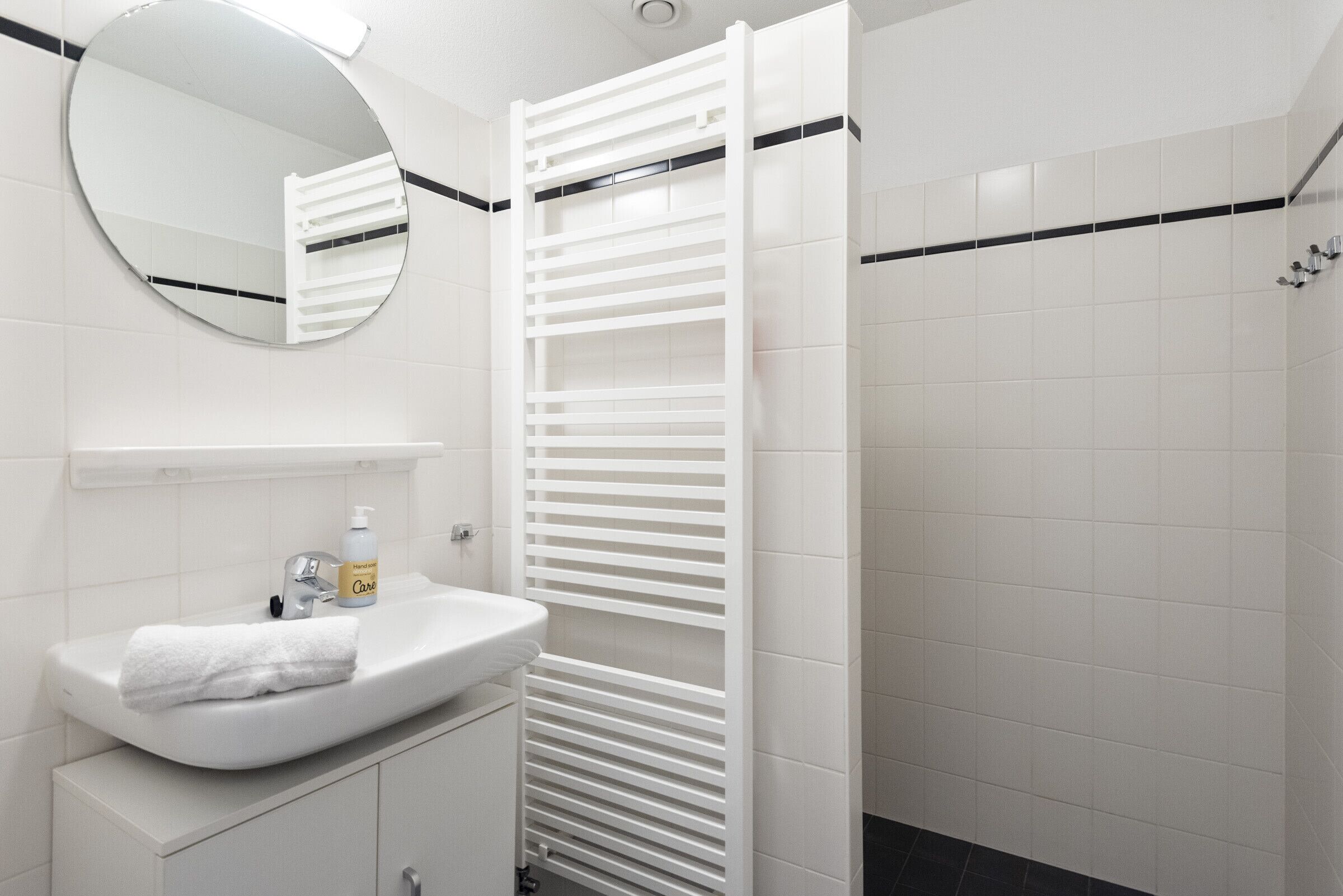 Een badkamer met een wit wastafelmeubel, een spiegel en een handdoek.