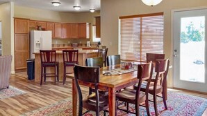A spacious kitchen with wooden cabinets, a dining area with a wooden table and chairs, and a large window with blinds.