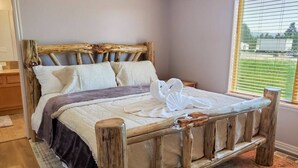 A rustic wooden bed with a headboard, a bedside table, and a window with blinds.