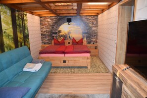 Een slaapkamer met een bed, een blauwe bank, een televisie en een muurschildering.
