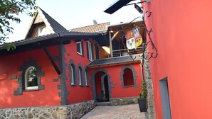 Een rood gebouw met stenen details, een pannendak en een balkon met een vlag.