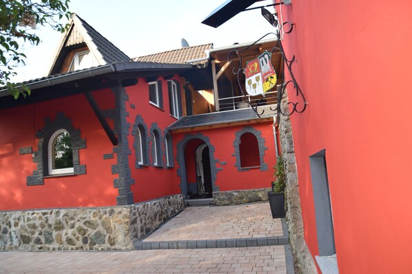 Een rood gebouw met stenen details, een pannendak en een balkon met een vlag.