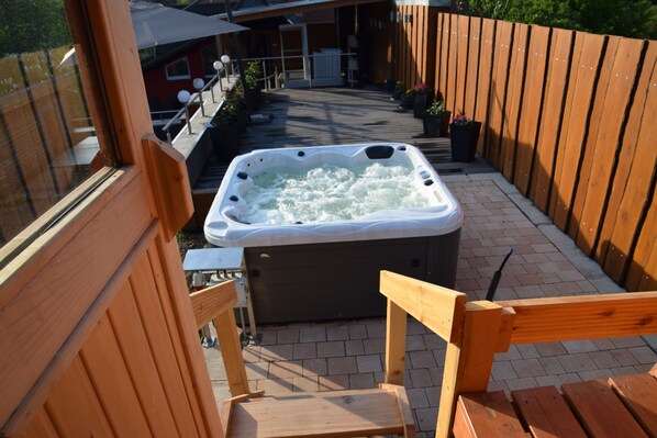 A hot tub in a wooden deck area with a view of a house in the background.