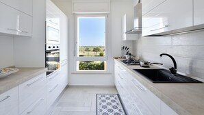 A modern kitchen with white cabinetry, a black sink, and a window with a view of greenery. - Sea view five minutes from the beach IUN Q5161 (Quartu Sant'Elena)
