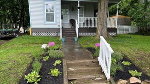 Un jardin devant une maison, avec un chemin menant à un porche.