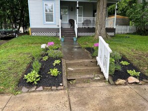 A front yard with a pathway leading to a house with a porch.
