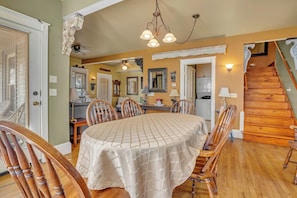 A dining area with a round table, chairs, and a chandelier.