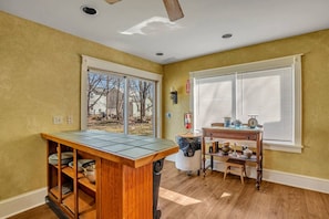 A kitchen with a central island, a dining table, and a window with blinds.