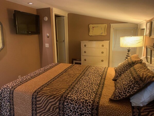 Une chambre à coucher avec un lit, une commode, un téléviseur et une lampe.