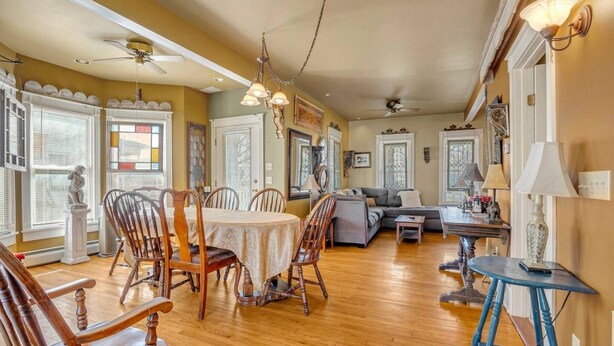 Un salon spacieux comprenant un coin repas, un plancher en bois et divers types de sièges, notamment un canapé, des fauteuils et une table.