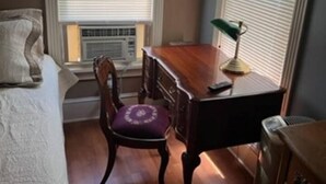 Une pièce comprenant un lit, un bureau, une chaise et un radiateur.