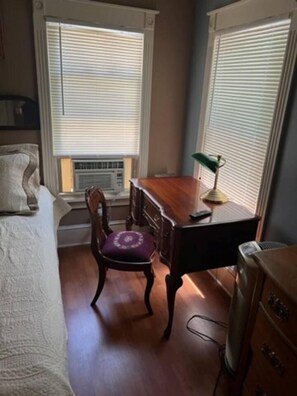 A room with a bed, a desk, a chair, and a radiator.