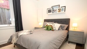 A bedroom with a bed, nightstands, a window with curtains, and wall-mounted pictures. - Stylish 1BR oasis with AC, laundry, next to park! (Washington)
