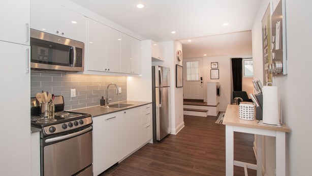 A modern kitchen with stainless steel appliances, white cabinetry, and a wooden floor. - Stylish 1BR oasis with AC, laundry, next to park! (Washington)