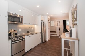 A modern kitchen with stainless steel appliances, white cabinetry, and a wooden floor. - Stylish 1BR oasis with AC, laundry, next to park! (Washington)