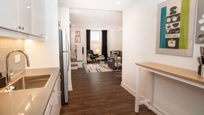 A modern kitchen with a sink, cabinets, and a dining area with a sofa and table. - Stylish 1BR oasis with AC, laundry, next to park! (Washington)