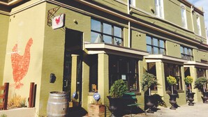 A two-story building with a green facade, large windows, and a visible storefront with potted plants. - Stylish 1BR oasis with AC, laundry, next to park! (Washington)