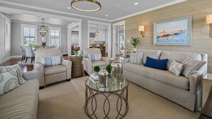 A spacious living room with a large sofa, a coffee table, and a dining area with chairs and a table.