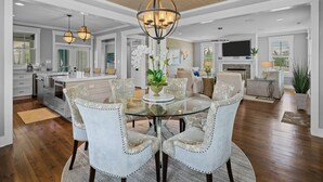 A spacious kitchen with a central island, a dining area with a glass table, and a living room with a fireplace.