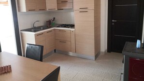 Una cucina compatta con mobili in legno chiaro, un fornello a gas e un lavello.