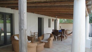 Un'area salotto esterna coperta con mobili in vimini, un tavolo e sedie.