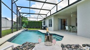 A backyard with a swimming pool, outdoor furniture, and a bottle of champagne. - Family Disney Paradise with Pool & Game Room  (Davenport)